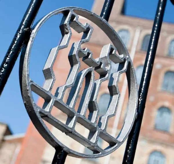 The ironwork roundel on the mill gates, with the mill building behind